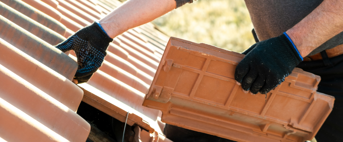 Man replacing brick singles of a roof.